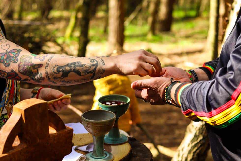 Curate offering communion to parishioner in a woodland setting