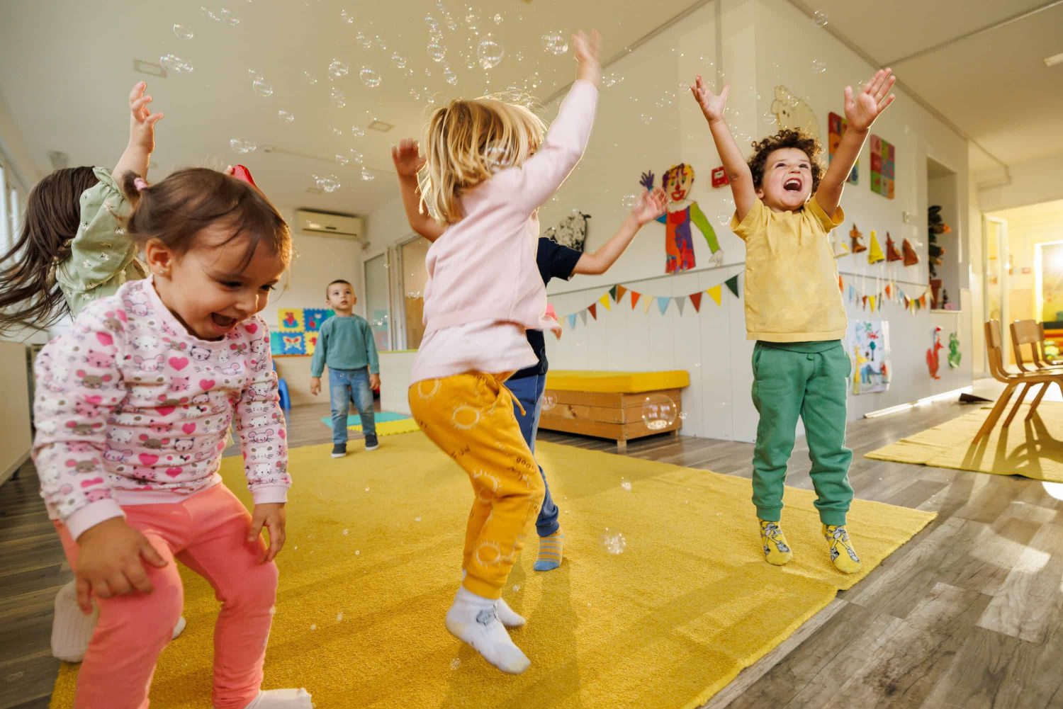 Group of happy children having fun playing whit soap bubbles in playroom