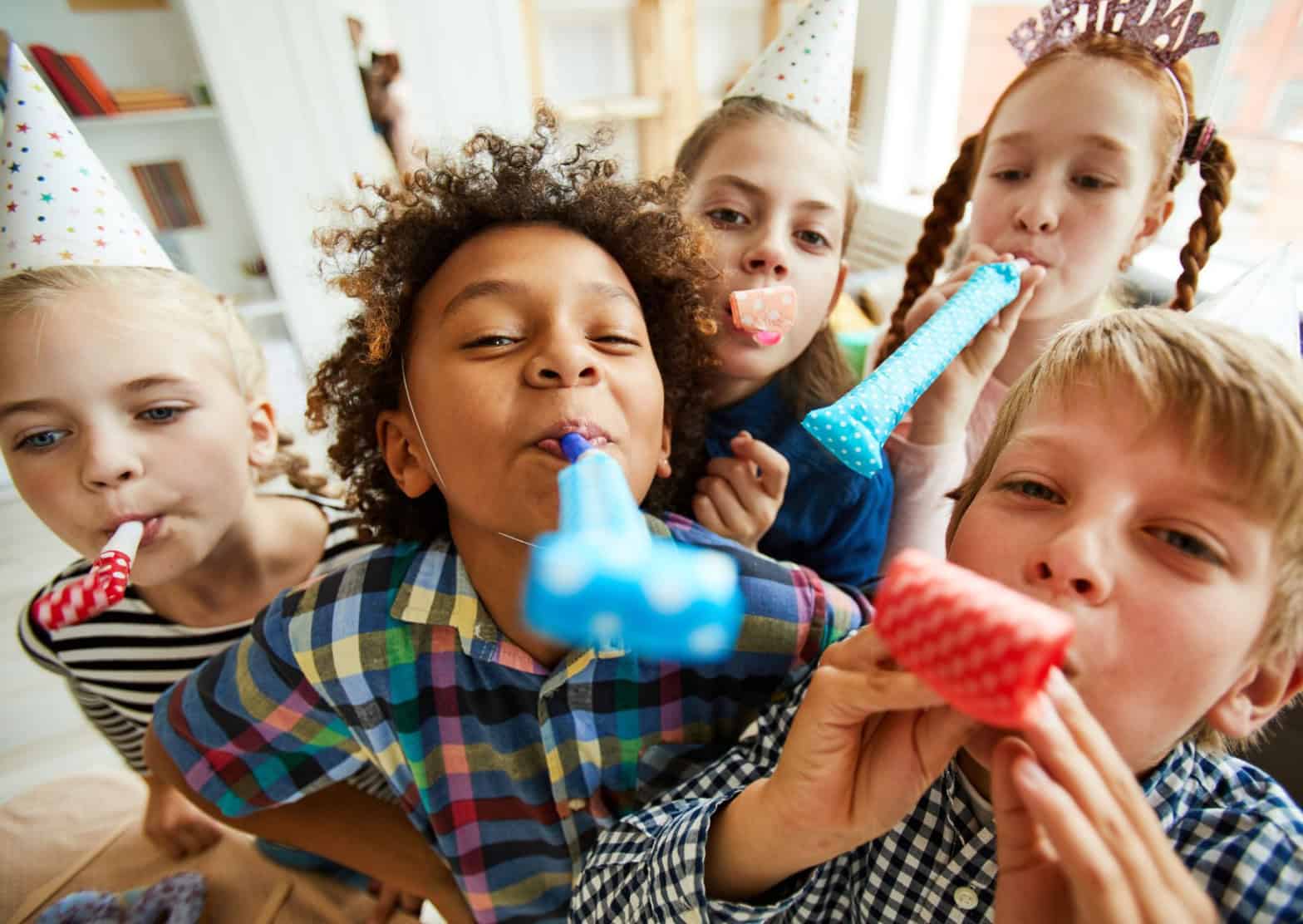 children with party hats on and party blowers