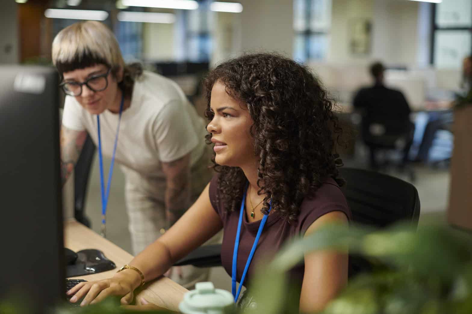 Two ladies looking at a computer on a desk depicting working together