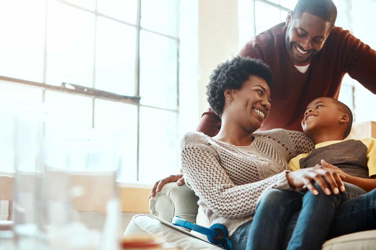 A Mother, Father and young son together at home. The Mother is holding the son smiling at him.