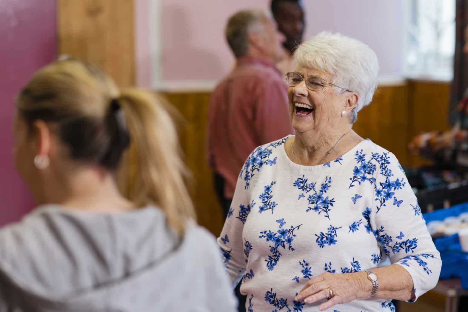 A senior age lady smiling in a community church environment