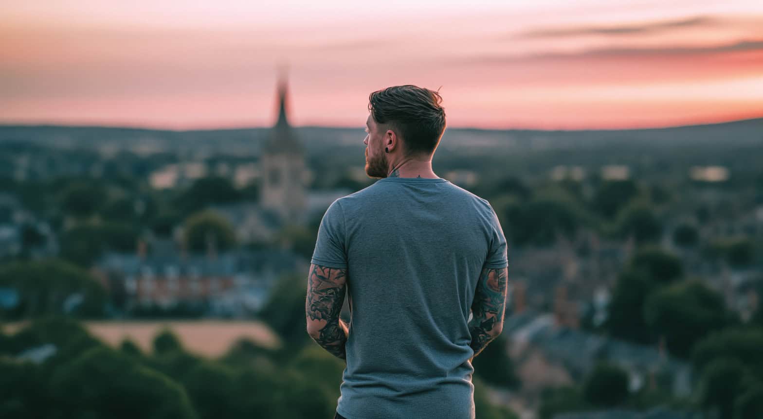 A young man looks out optimistically to the horizon with a orange glowing sunset