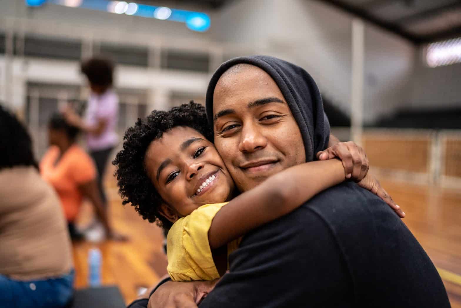 A young daugter embracing her father whilst both smile at the camera