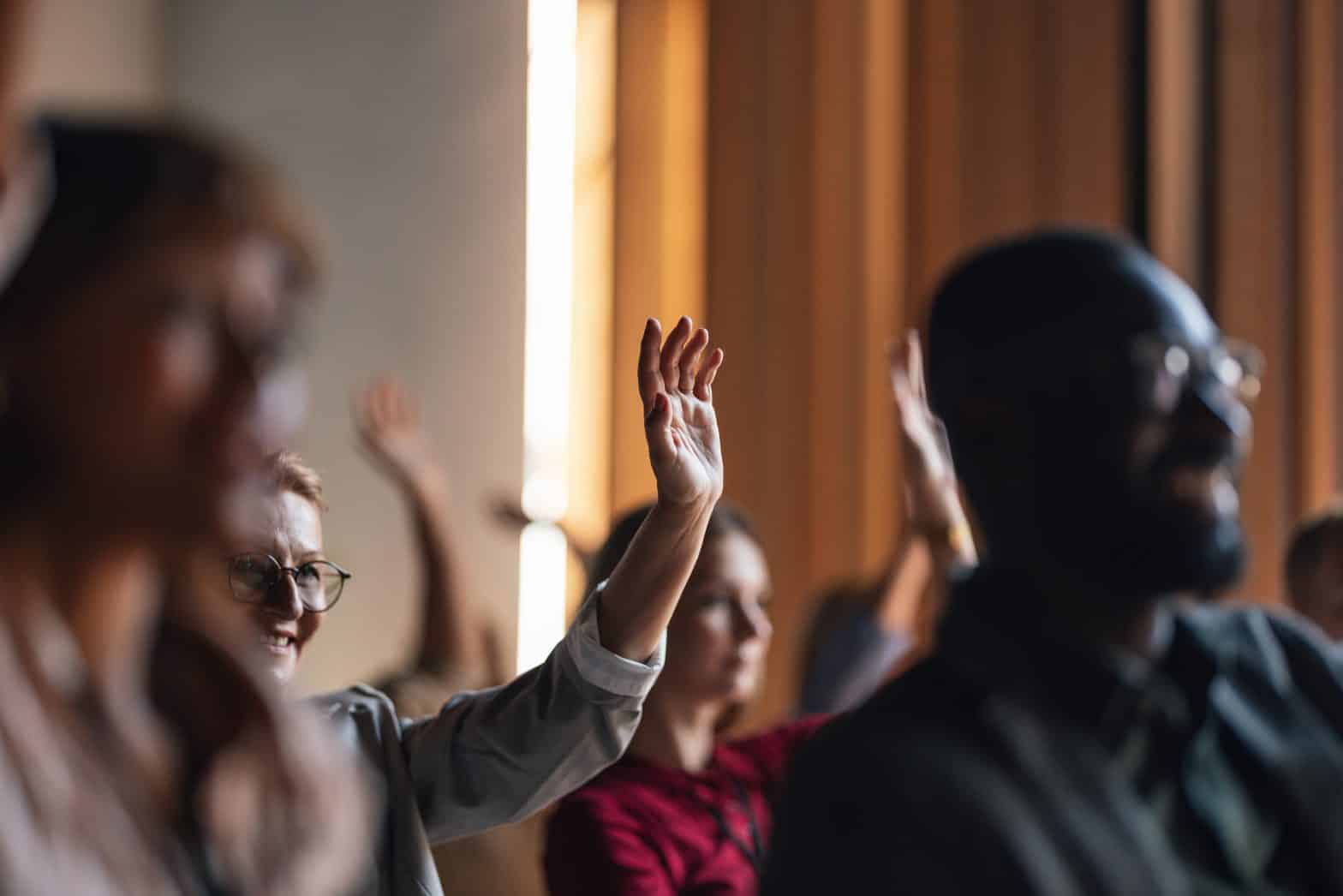 A group of diverse adults raise their hands in the air